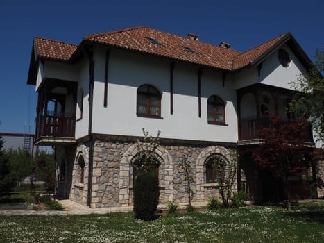 Stanisici, Bijelina, Bosnia and Herzegovina, April 25, 2021. Old Serbian house. Stone foundation. Wooden screeds on the walls. Tile roof. Carved terraces. Round attic window. Sights of the Balkans.