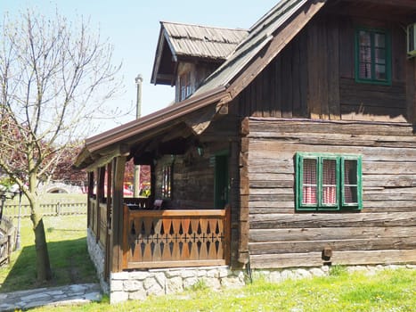 19th century Bosnian mountain traditional dwelling. Restored ethno building, Wooden deck, kitchen checkered curtains.
