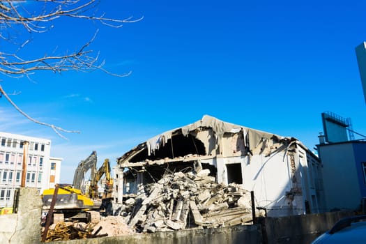 Demolition of a old building with sloopkraan against blue clouds sky.
