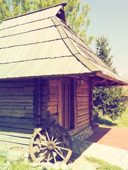 Stanisici, Bijelina, Bosnia and Herzegovina, 25 April 2021. Log village farmhouse. 19th century Bosnian mountain traditional dwelling. Restored ethno building. Antique wooden wheel from chariot.