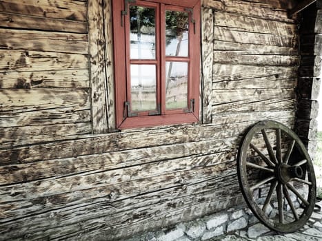 Stanisici, Bijelina, Bosnia and Herzegovina, 25 April 2021. Log village farmhouse. 19th century Bosnian mountain traditional dwelling. Restored ethno building. Antique wooden wheel from chariot.