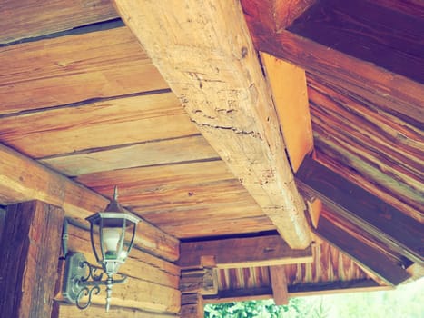 Woodworking for construction and roofing. Wooden beam and roof in a traditional peasant house. Metal lantern on the wall. Wooden architecture. Stanisici, Bijelina, Bosnia and Herzegovina