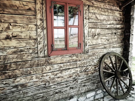 Stanisici, Bijelina, Bosnia and Herzegovina, 25 April 2021. Log village farmhouse. 19th century Bosnian mountain traditional dwelling. Restored ethno building. Antique wooden wheel from chariot.