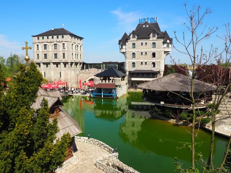 Stanisici, Bijelina, Republika Srpska, Bosnia and Herzegovina April 25 2021 Ethno village, tourism and attractions. Stone and wooden buildings of the hotel. People visit restaurant, traditional houses