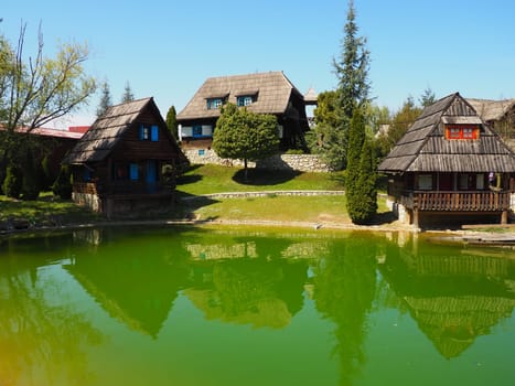 Stanisici, Bijelina, Bosnia and Herzegovina. April 25, 2021 Ethno-village, traditional village houses made of logs, Bosnian style of construction in the highlands. Lake with water. Wooden architecture