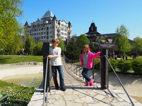 Stanisici, Bijelina, Bosnia and Herzegovina April 25 2021 A boy 8 years old and girl 7 years old, brother and sister, stand at the suspension bridge in the ethno village. Children visit tourist sites.