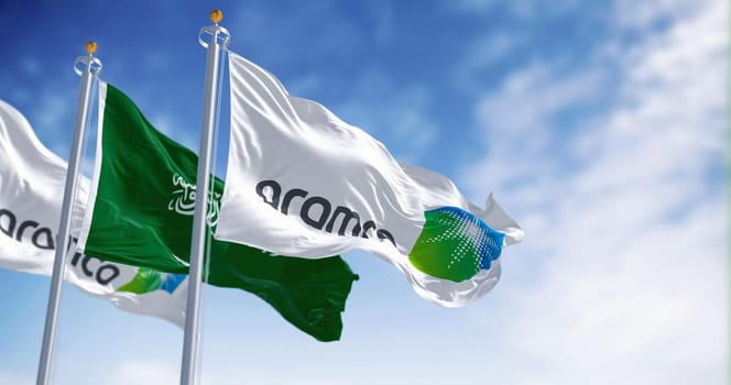 Dhahran, SA, march 2023: Flags of Aramco and Saudi Arabia waving on a clear day. Aramco is the Saudi national hydrocarbon company. Illustrative editorial 3d illustration render
