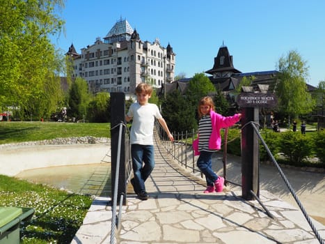 Stanisici, Bijelina, Bosnia and Herzegovina April 25 2021 A boy 8 years old and girl 7 years old, brother and sister, stand at the suspension bridge in the ethno village. Children visit tourist sites.
