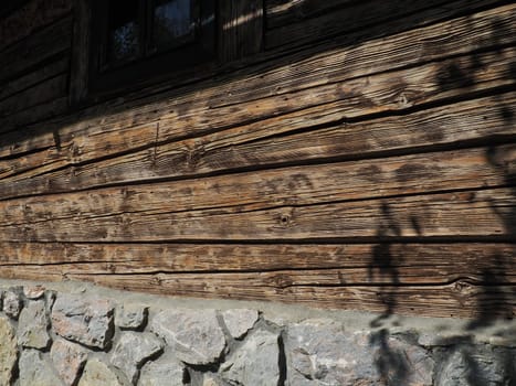 Log wooden wall of an old village house. Cobblestone foundation. Old methods of construction of residential buildings
