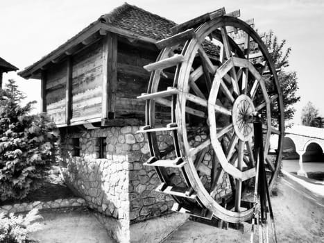 Wooden water mill. A hydraulic structure using hydropower from a water wheel. Useful work by means of a gear train.