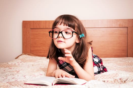 Little girl reading a book at home
