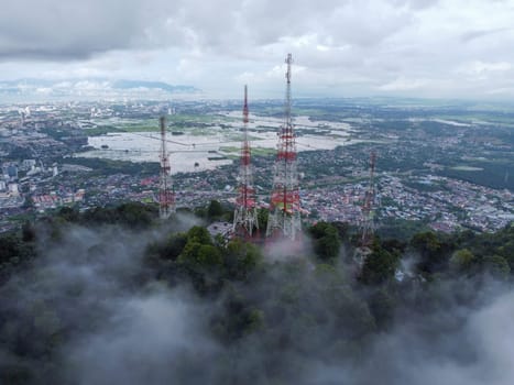 Aerial view telecommunication tower at hill top with background of residential house