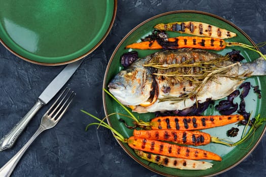 Baked dorado fish or sea bream with grilled vegetables on concrete background. Flat Lay