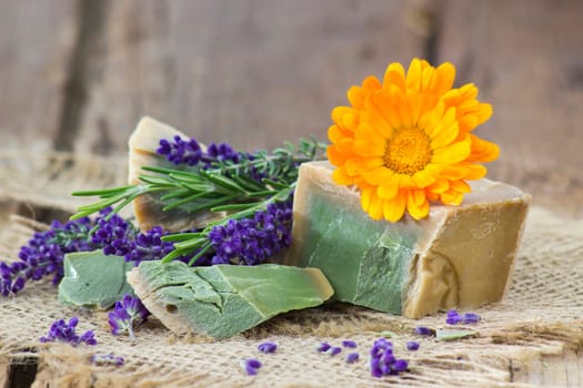 Natural handmade soap with calendula, lavender and herbs on rustic wooden background