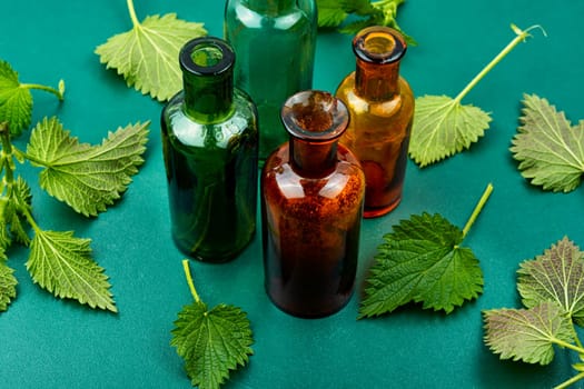 Fresh nettle leaves and pharmacy bottle on the table. Medicinal plant