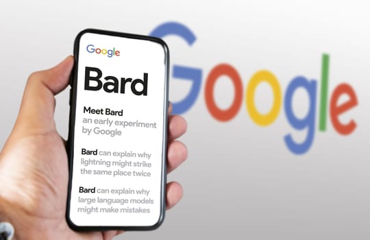 San Francisco US, Feb 2023: A hand holding a phone with the Google Bard website on the screen. White background with blurred Google logo. Bard is Google artificial intelligence chatbot