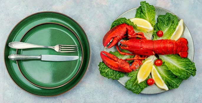 Boiled large lobster with greens and lemon on a tray. Seafood