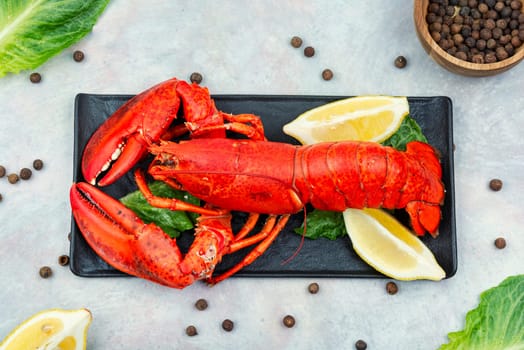 Boiled large lobster with greens and lemon on a tray. Seafood