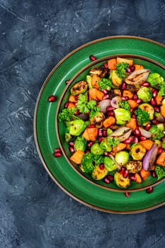 Salad with roasted Brussels sprouts, carrots, garnished with herbs and pomegranate seeds. Vegetable salad on plate