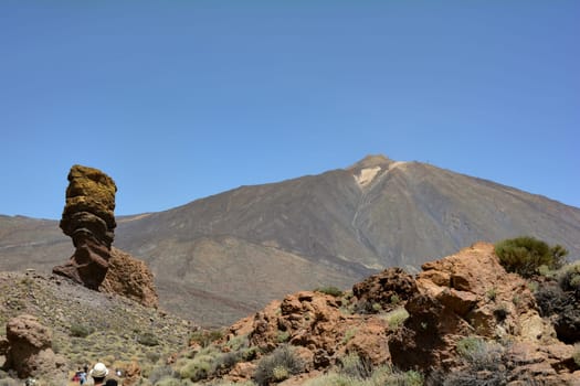 The bizarrely shaped Roque Cinchado rock of volcanic rock in Teide National Park on the Canary Island of Tenerife, Spain. With views of Mount Teide and blue skies.