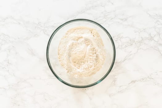 Top view of a mixing bowl filled with flour for Chocolate Ginger Sugar Cookie Dough preparation, sitting alone on a marble countertop.