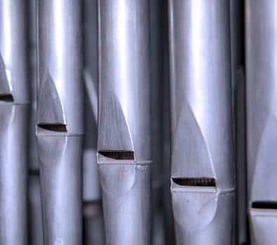 Many organ pipes stand side by side in an organ over a bellows.