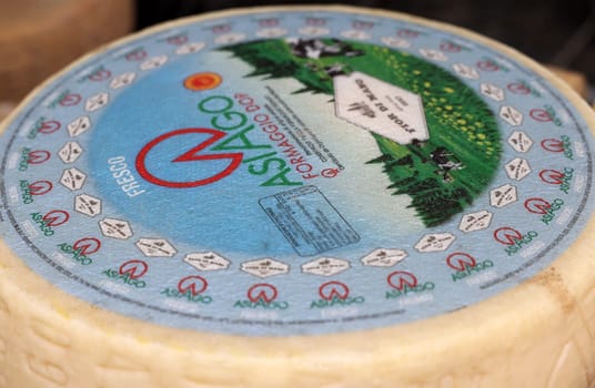Cremona, Italy - September 7, 2022: Whole wheels of Asiago cheese sold at a street stall during the farmers market in Cremona, Lombardy, Italy