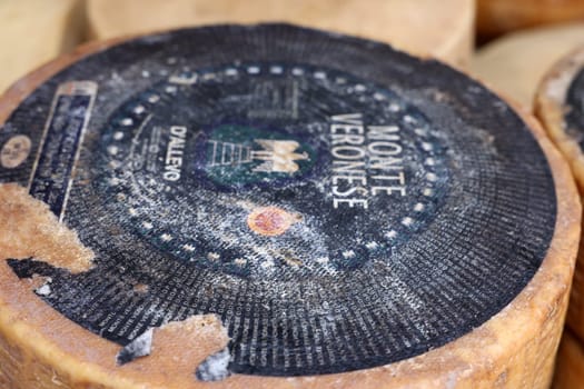 Cremona, Italy - September 7, 2022: Whole wheels of Monte Veronese cheese sold at a street stall during the farmers market in Cremona, Lombardy, Italy