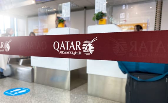 Doha, QA Jan 2023: Red barrier tape with the Qatar Airways logo inside an airport. Qatar Airways is a state-owned flag carrier airline of Qatar. Travel and airport security. Illustrative editorial
