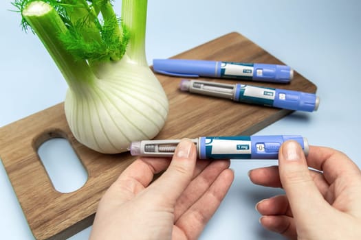 Hands holding Insulin injection pen and fennel vegetable root for diabetics and weight loss. High quality photo