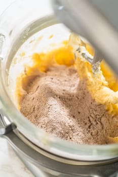 Dry ingredients, including flour and cocoa, added to the wet mixture in the stand mixer for Chocolate Ginger Sugar Cookie Dough, ready for final mixing.