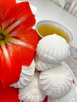 a few marshmallows on a saucer, a cup of fragrant tea and an amaryllis flower