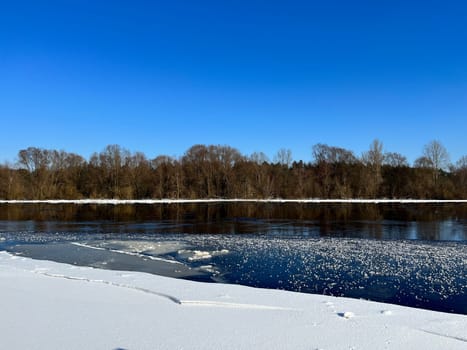 embankment of the river in winter, on the other side of the oak forest