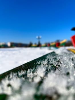 under the snow, colorful benches in winter on the city embankment