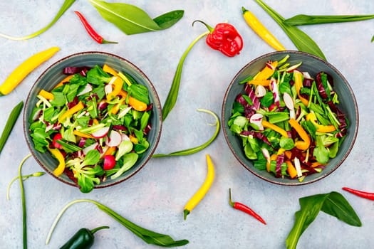 Healthy salad bowl with vegetables and bear leek or wild garlic on a rustic wooden board.