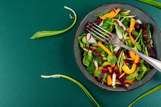 Healthy salad bowl with vegetables and bear leek or wild garlic on a rustic wooden board.