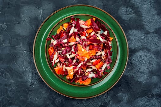 Fresh red chicory salad with orange on a plate. Vegetarian meal. Copy space