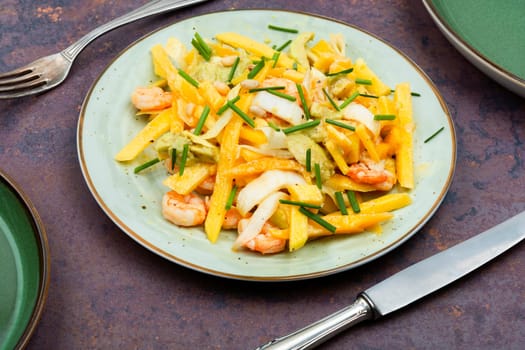 Delicious salad of mango, avocado, shrimp and pine nuts served on plate.