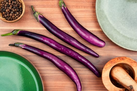 Raw small eggplants on a wooden table. Diet menu concept. Top view