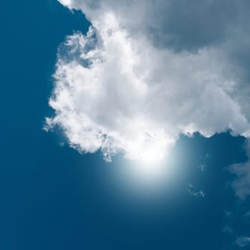 big white cloud with the sun in the background on a warm summer day