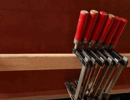 carpentry clamps with red handles hang on a shelf in a carpentry workshop
