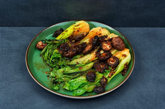 Chinese fried Pak Choi with shitake mushrooms and chopstick. Vegan food, close up