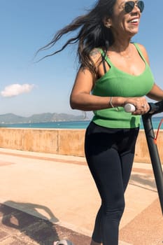 young latina woman having fun with electric scooter by the beach