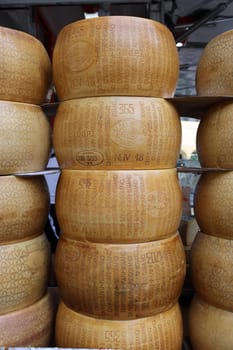 Cremona, Italy - September 7, 2022: Whole wheels of Parmigiano Reggiano cheese sold at a street stall during the farmers market in Cremona, Lombardy, Italy