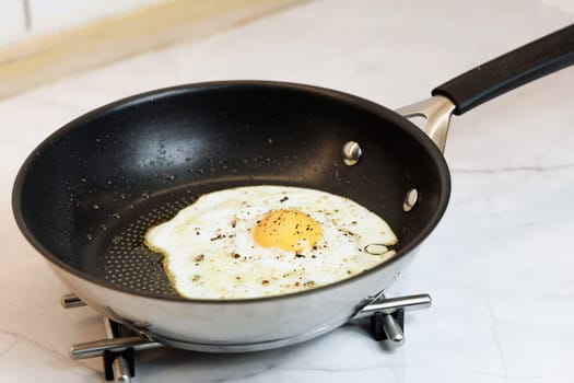 Breakfast served on the kitchen table with a fried egg in a frying pan. High quality photo