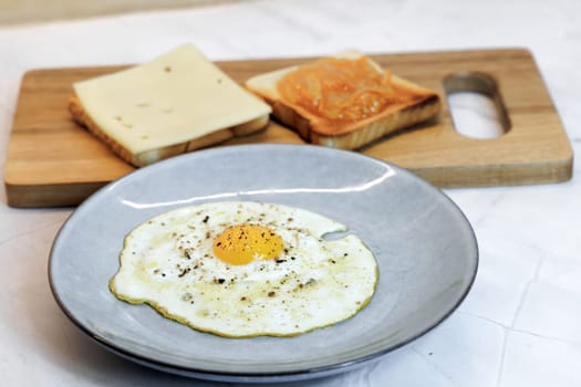 Breakfast served on the kitchen table with a fried egg on a plate and fresh bread and coffee. High quality photo