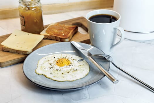 Breakfast served on the kitchen table with a fried egg on a plate and fresh bread and coffee. High quality photo