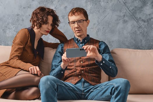 Middle aged man shows to his wife how to control their smart home from smartphone
