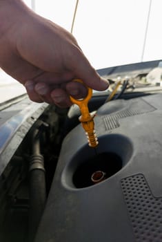 Man checking his oil level from old diesel engine. Petrol station background
