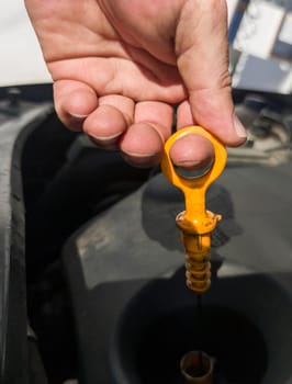 Man checking his oil level from old diesel engine. Petrol station background